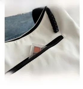 Détail du sac cabas blanc montrant la poche zippée noire et sa capacité de rangement