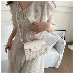 Detail of straw crossbody bag with floral embroidery and cream leather flap