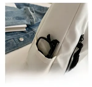 Détail d'une poche latérale sur un sac fourre-tout blanc contenant des lunettes noires