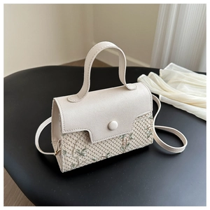Detailed close-up of cream leather woven handbag with intricate floral embroidery details