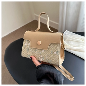 Detail of beige straw crossbody bag with floral embroidery and ergonomic handle