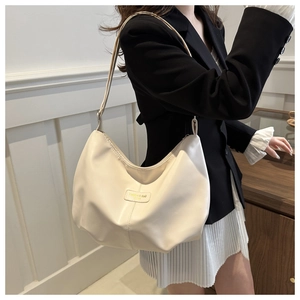 Détail d'un sac cabas nuage beige montrant la texture plissée et la plaque dorée