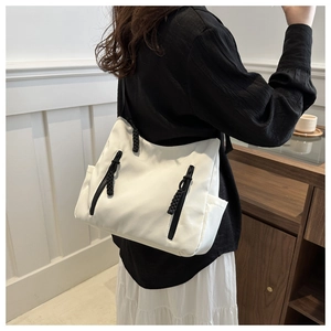 Détail d'un cabas en nylon blanc avec fermetures éclair noires et tirettes en corde