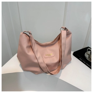 Détail du sac fourre-tout rose pêche montrant le nylon lisse et l'étiquette de mode