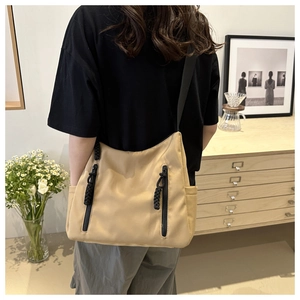 Détail du sac bandoulière en nylon kaki avec fermetures éclair porté sur l'épaule