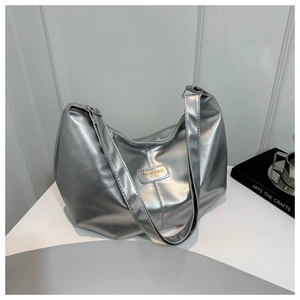 Détail du sac hobo argenté métallisé avec plaque logo dorée et fermeture zippée