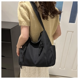 Détail du grand sac porté épaule noir avec deux fermetures éclair et pompons tissés