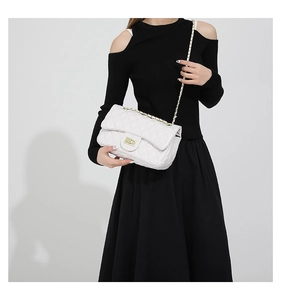Model wearing white quilted crossbody bag with gold chain and diamond pattern