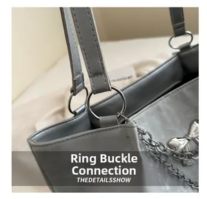 Detailed shot of silver ring connection and bow charm on a grey tote shoulder bag