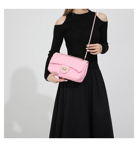 Detailed close-up of pink quilted leather shoulder bag with gold chain strap on model