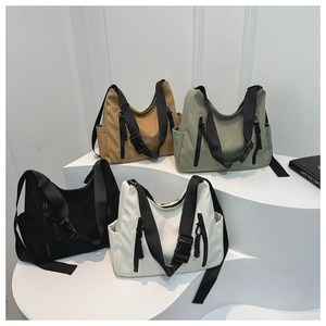 Quatre couleurs de sacs à bandoulière en nylon sur un présentoir blanc minimaliste