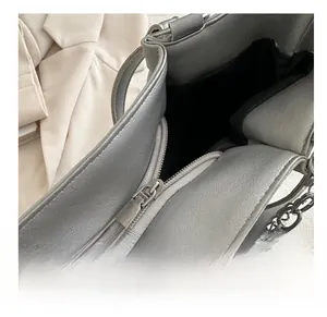 Detail shot of smooth silver zipper and metallic chain link on minimalist shoulder bag