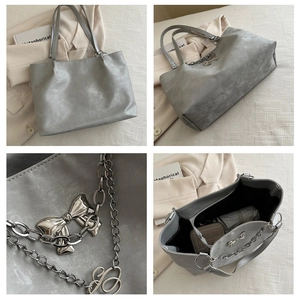 Macro shot of silver metallic tote bag showing bow buckle and chain detail
