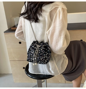 Détail d'un sac seau noir à paillettes avec accents de perles et bandoulière chaîne
