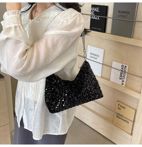 Détail d'un sac hobo chic à paillettes noires avec une bandoulière en chaîne argentée