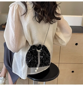 Dettaglio borsa a secchiello con paillettes nere, catena argento e coulisse di perle