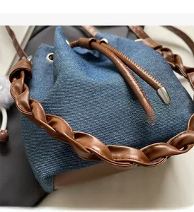 Detail of denim bucket bag showing woven leather handle and drawstring closure