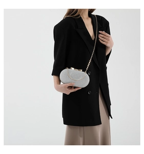 Macro detail of silver glitter clutch bag with elegant golden bow clasp and chain strap