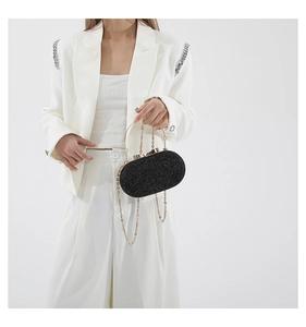Close-up of black glitter evening clutch bag with gold round handle and chain strap