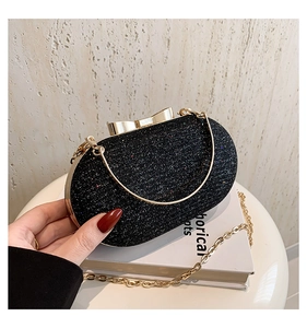 Detail of black sequin clutch bag with gold bow clasp and metallic chain strap