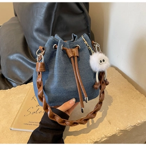 Detail of denim bucket bag showing drawstring closure and brown woven handle texture