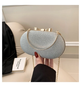 Detail of glitter silver evening bag featuring a gold bow clasp and chain strap