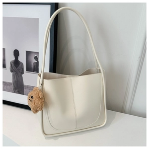 Dettaglio della borsa tote minimalista bianco avorio con ciondolo a forma di orsetto