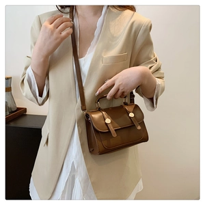 Classic brown leather handbag with vintage gold buckle on a chic beige blazer outfit