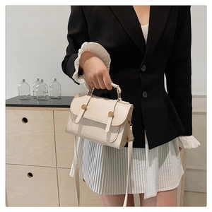 Detail of off-white leather handbag showing golden buckles and fixed top handle grip