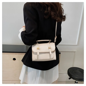 Detail view of cream white crossbody small square bag with golden studs on a model