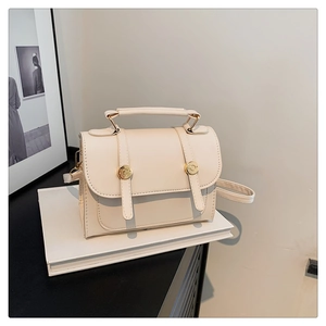 Detail of cream vintage crossbody bag showing flap cover and gold button hardware