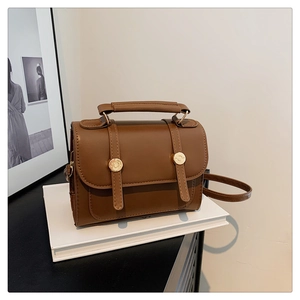 Close-up of vintage brown crossbody bag with matte leather and gold buckle detail