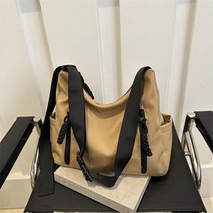 Grand sac fourre-tout en nylon kaki avec boucle tactique sur une chaise en cuir