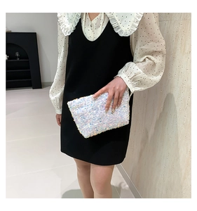 Fashionable sequined hand clutch bag showing iridescent white sparkles in casual setting