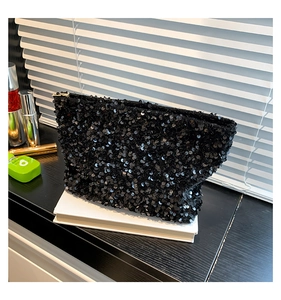 Macro shot of shimmering black sequins and golden zipper detail on the trapezoid pouch