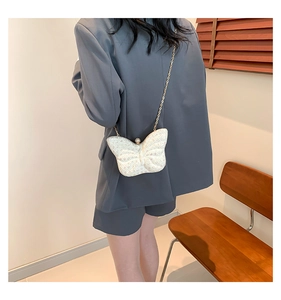 Détail du sac de soirée papillon à paillettes avec fermoir perle et chaîne sur modèle