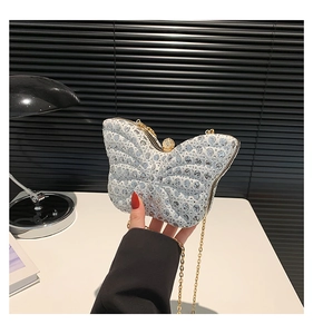 Détail de pochette papillon avec paillettes rondes, cadre doré et fermoir strass