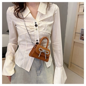Detailed view of mini brown crossbody bag with rhinestone bow and silver chain strap