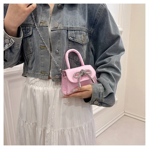 Detail of pink mini handbag featuring a sparkling rhinestone bow and silver chain strap