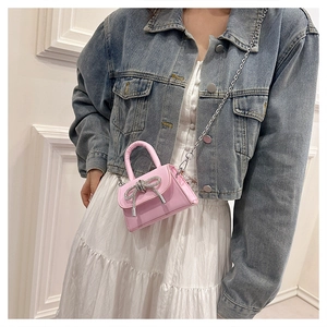 Detail of pink mini handbag with rhinestone bow showing stylish metal chain strap