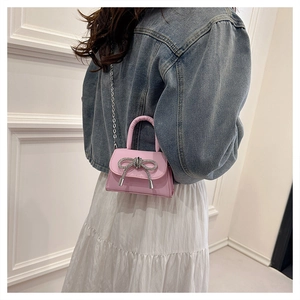 Close-up of pink mini handbag featuring a silver rhinestone bow and metal chain strap