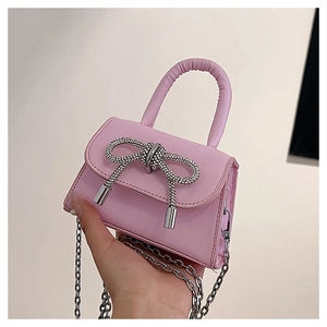 Detail of pink mini handbag featuring a sparkling rhinestone bow and silver chain strap