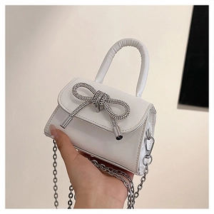 Macro shot of white PU leather square bag featuring a sparkling rhinestone bow and silver chain