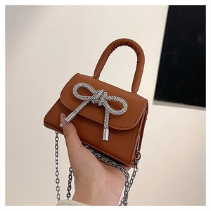 Detail of brown mini square handbag with sparkling silver rhinestone bow and chain