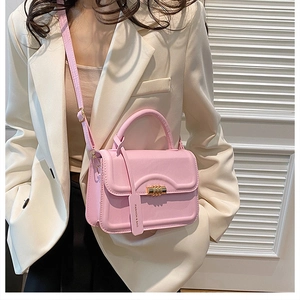 Detail of pink PU leather handbag with golden spiral lock and fashion tag on model