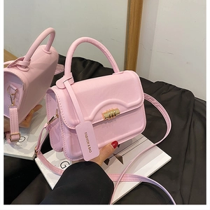 Pink crossbody handbag with wavy flap, golden metal buckle and decorative fashion tag