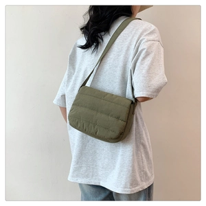 Detail of army green quilted puffer crossbody bag with stitched texture on wide strap