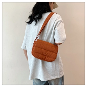 Detailed view of brown quilted crossbody bag with soft padded texture on model