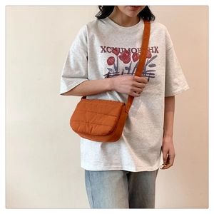 Detail of orange quilted padded crossbody bag with adjustable strap and flap closure
