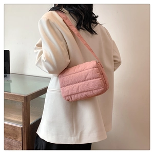 Detail of pink quilted puffer crossbody bag worn with beige suit for stylish daily outfit